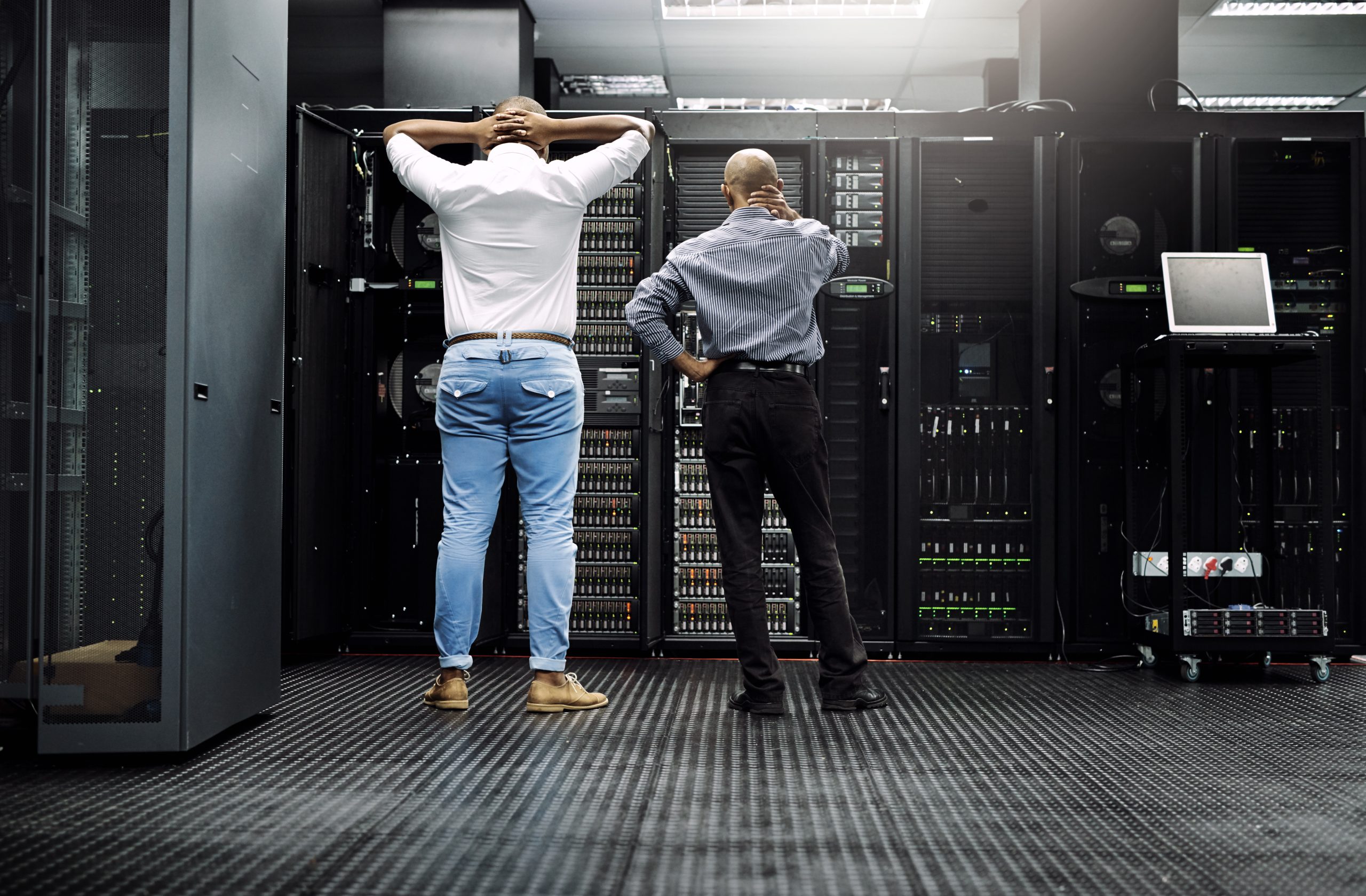 Rearview shot of two IT technicians having difficulty repairing a computer in a server room. backup & Disaster